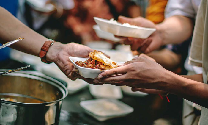 person handing someone a meal at a soup kitchen