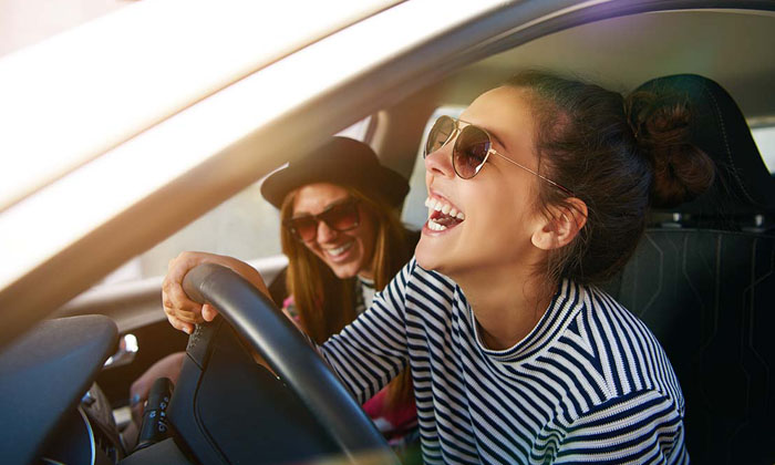 two women laughing as they ride in a new car
