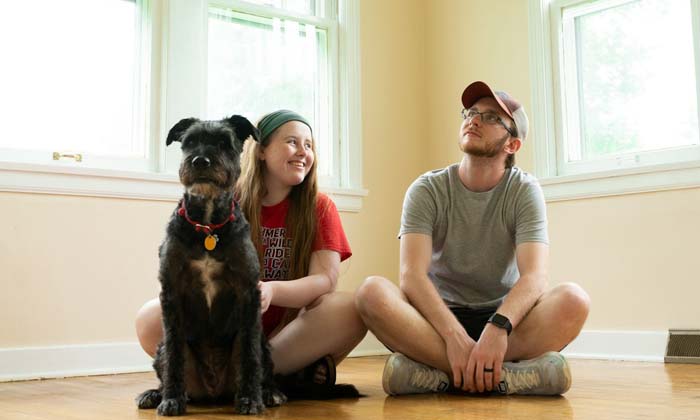 young couple with their dog sitting in the living room after moving into their first home